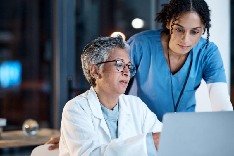 two female medical professionals looking at computer screen